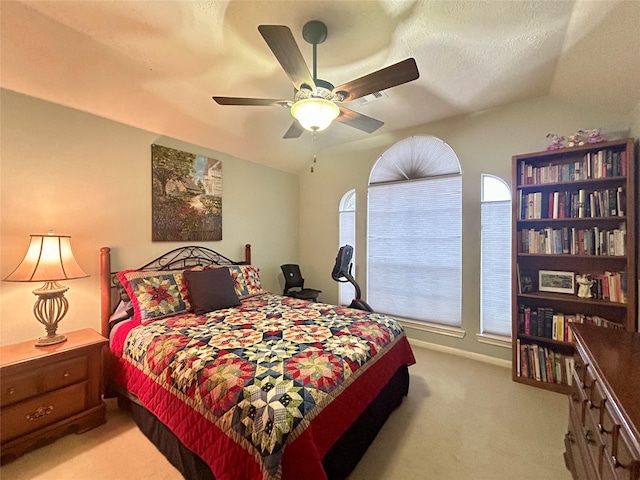 bedroom featuring a textured ceiling, vaulted ceiling, a ceiling fan, and light colored carpet