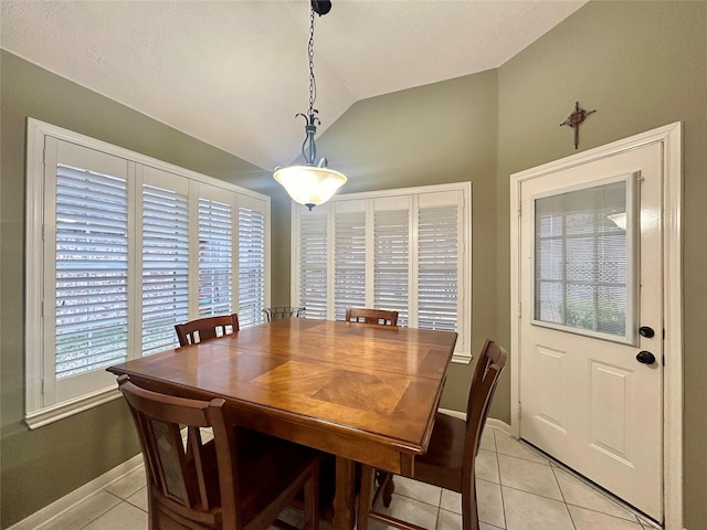 dining space featuring light tile patterned floors, lofted ceiling, and baseboards