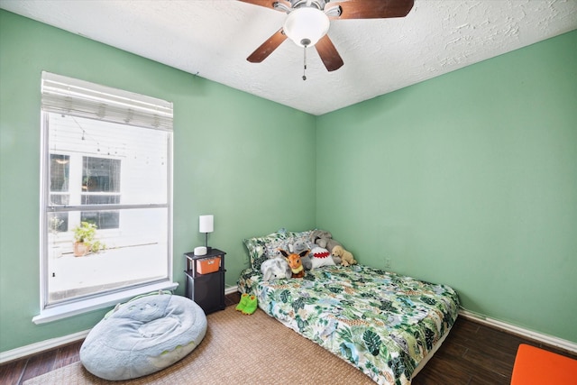 bedroom featuring ceiling fan, hardwood / wood-style floors, and a textured ceiling