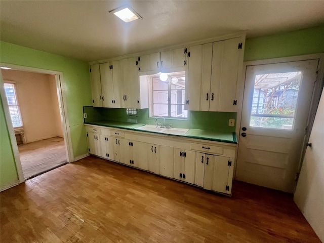 kitchen featuring tasteful backsplash, white cabinetry, sink, and light hardwood / wood-style flooring