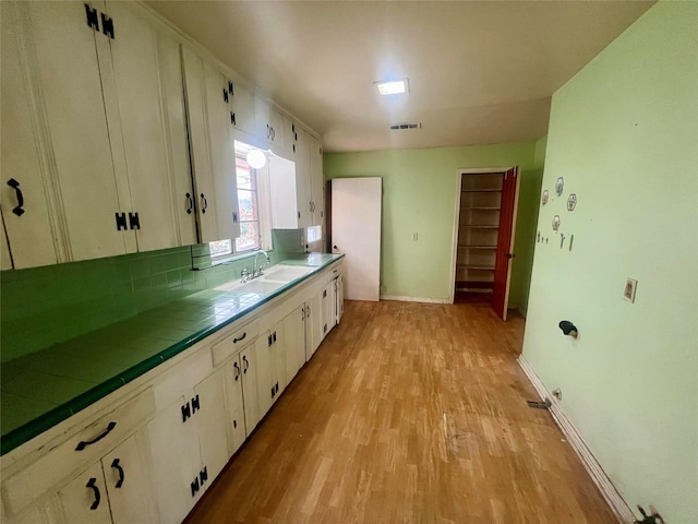 kitchen featuring white cabinetry, sink, tile countertops, and light hardwood / wood-style floors