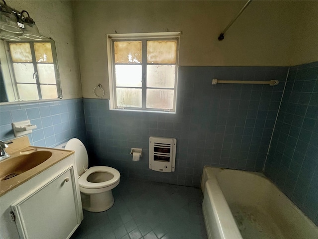 bathroom with a bathing tub, heating unit, vanity, toilet, and tile patterned floors