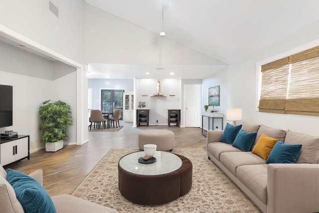 living room with high vaulted ceiling, a healthy amount of sunlight, and light hardwood / wood-style floors