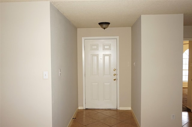 doorway to outside with tile patterned flooring and a textured ceiling