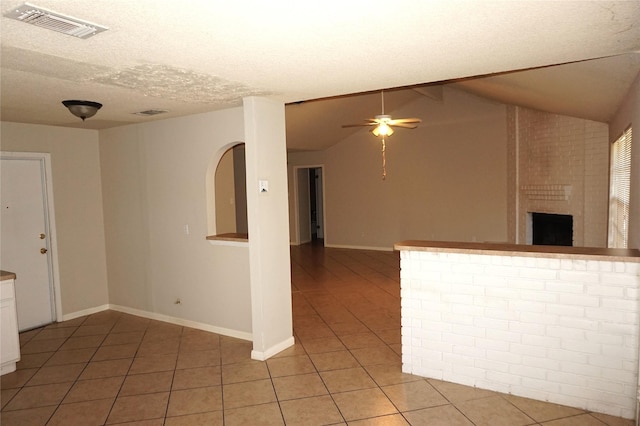 interior space with tile patterned flooring, vaulted ceiling, ceiling fan, and a textured ceiling