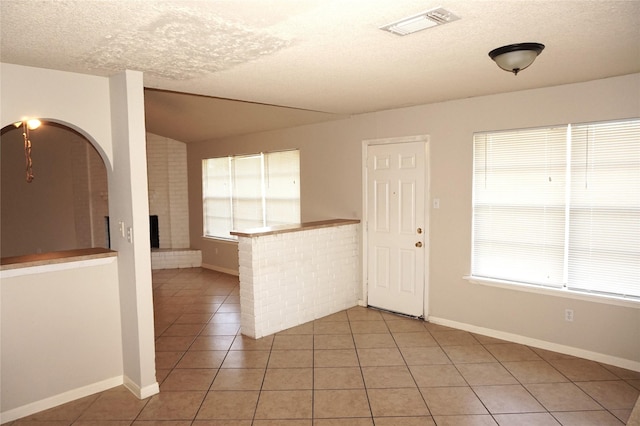 unfurnished room with light tile patterned floors, a fireplace, and a textured ceiling