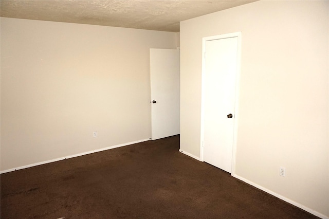 empty room featuring dark carpet and a textured ceiling