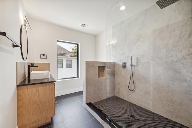 bathroom featuring tiled shower, vanity, and tile patterned flooring