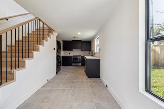 kitchen with stainless steel range with electric stovetop, sink, black fridge, and light tile patterned flooring