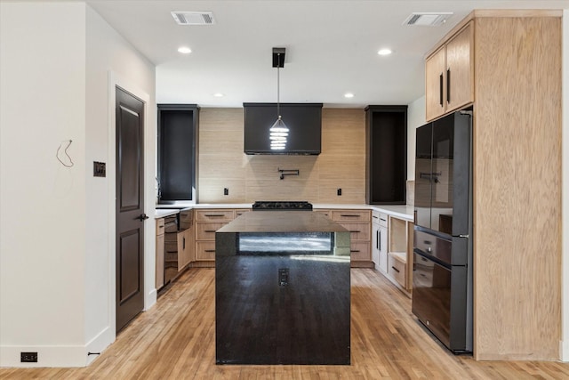 kitchen featuring tasteful backsplash, a center island, light brown cabinets, pendant lighting, and black appliances