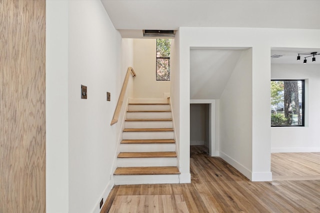 staircase with wood-type flooring, lofted ceiling, and a wealth of natural light