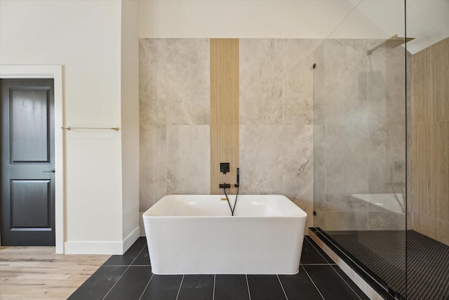 bathroom with independent shower and bath, tile patterned flooring, and tile walls