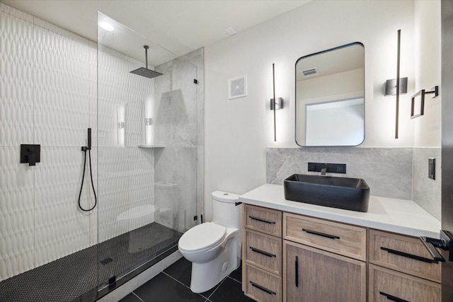 bathroom with tile patterned flooring, backsplash, tiled shower, vanity, and toilet