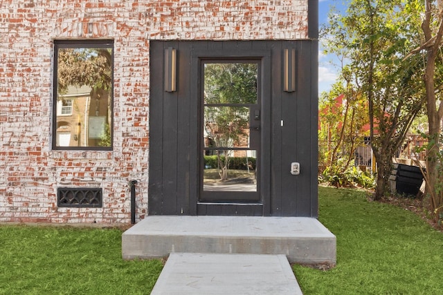 view of exterior entry with a lawn