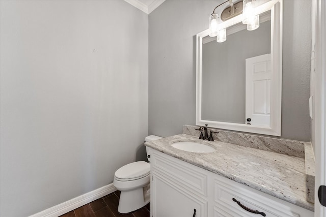 half bath featuring toilet, ornamental molding, vanity, wood finished floors, and baseboards