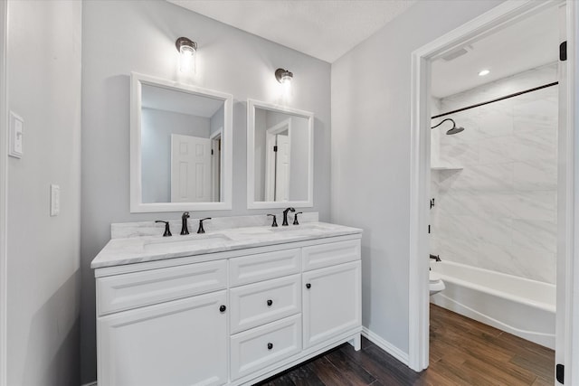 full bathroom with double vanity, toilet, a sink, and wood finished floors