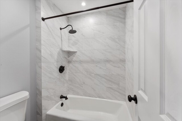 bathroom with toilet and tiled shower / bath