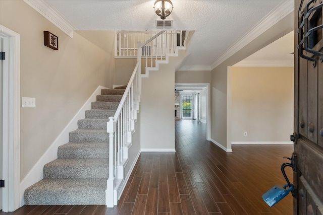 entrance foyer with ornamental molding, dark wood-type flooring, and a textured ceiling