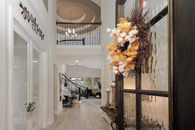 foyer entrance featuring wood-type flooring, a chandelier, and a high ceiling