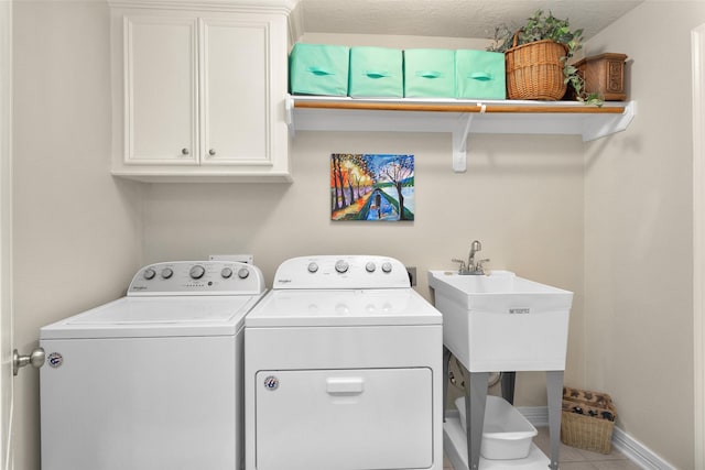 laundry room with sink, washing machine and dryer, cabinets, and light tile patterned flooring