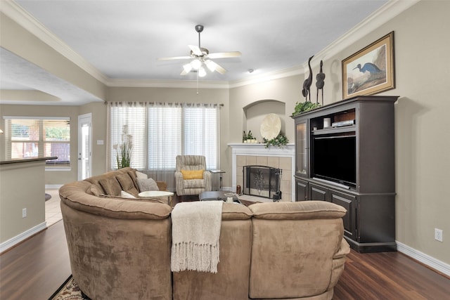 living room with a tiled fireplace, ornamental molding, and dark hardwood / wood-style flooring