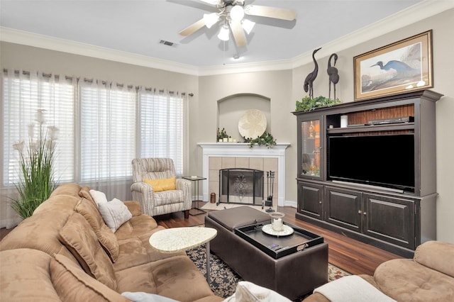 living room featuring crown molding, ceiling fan, dark hardwood / wood-style flooring, and a tile fireplace