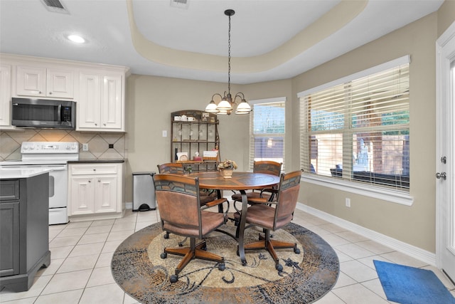 dining area with an inviting chandelier, light tile patterned floors, and a raised ceiling