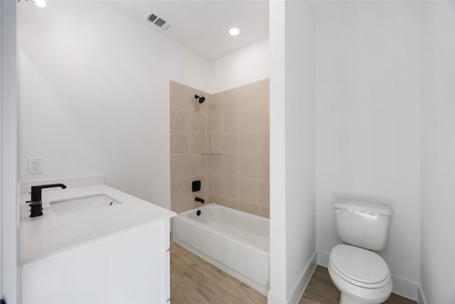 full bathroom with vanity, tiled shower / bath combo, wood-type flooring, and toilet