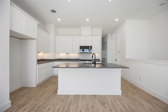 kitchen featuring white cabinetry, sink, a center island with sink, and light wood-type flooring