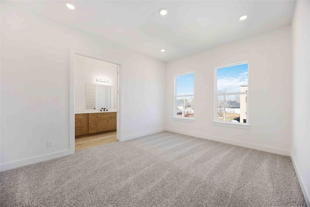 unfurnished bedroom featuring ensuite bathroom and light carpet