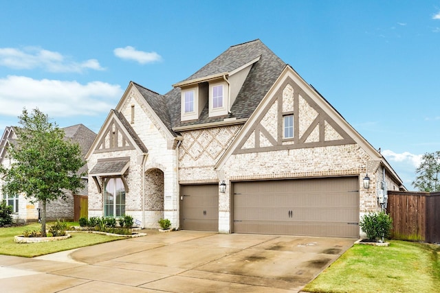 english style home featuring a garage and a front yard