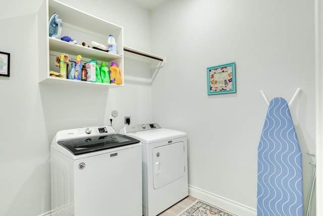 laundry area with separate washer and dryer and light hardwood / wood-style flooring