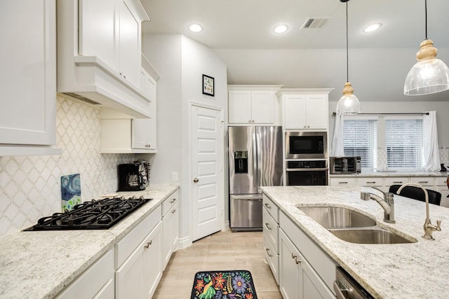 kitchen featuring appliances with stainless steel finishes, sink, white cabinets, hanging light fixtures, and light stone counters