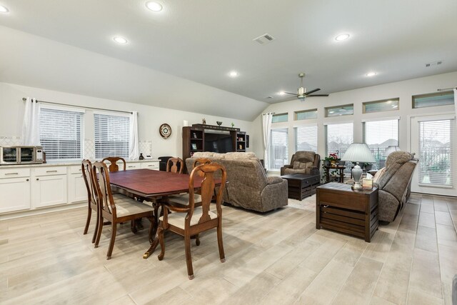 dining room with light hardwood / wood-style flooring, vaulted ceiling, and ceiling fan