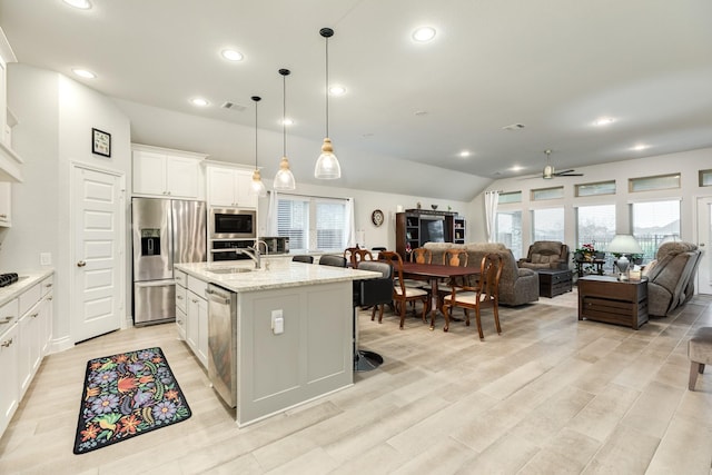 kitchen featuring sink, decorative light fixtures, a center island with sink, appliances with stainless steel finishes, and white cabinets