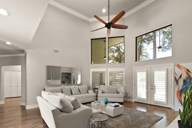 living room featuring hardwood / wood-style flooring, crown molding, and a towering ceiling