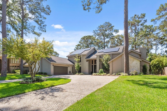 view of front of property featuring a garage, a front lawn, and solar panels