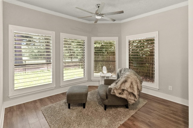 sitting room with a textured ceiling, dark wood-type flooring, ornamental molding, and ceiling fan