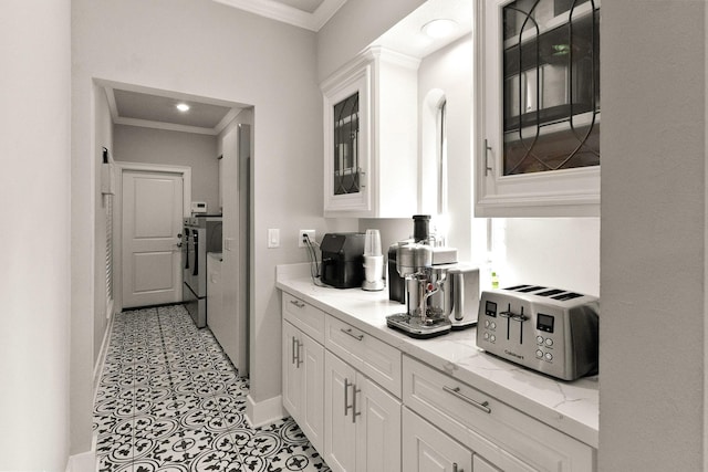 kitchen with white cabinetry, washing machine and clothes dryer, ornamental molding, and light stone counters