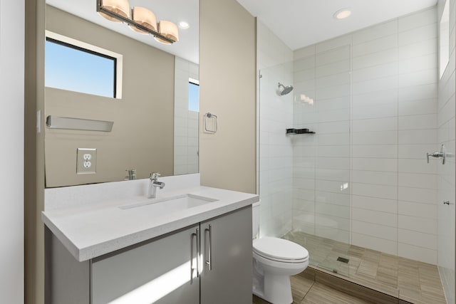 bathroom with vanity, toilet, and a tile shower