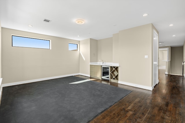 empty room featuring bar, beverage cooler, and dark hardwood / wood-style flooring