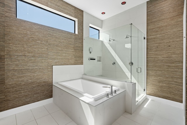 bathroom with plus walk in shower, tile patterned flooring, and tile walls