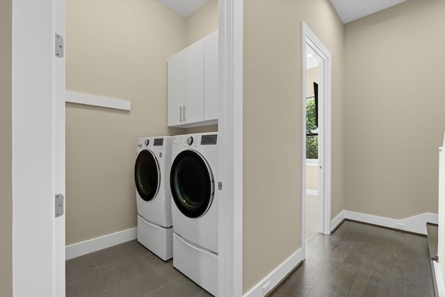 clothes washing area with dark wood-type flooring, cabinets, and washing machine and clothes dryer