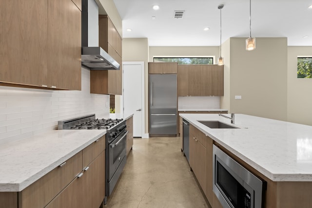 kitchen with sink, built in appliances, hanging light fixtures, wall chimney range hood, and backsplash