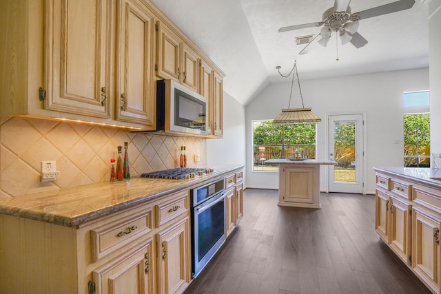 kitchen featuring light stone counters, appliances with stainless steel finishes, a center island, and pendant lighting