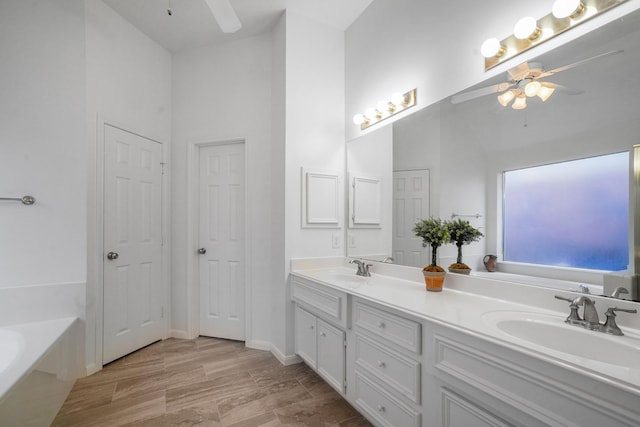 bathroom with a high ceiling, vanity, a bath, and ceiling fan