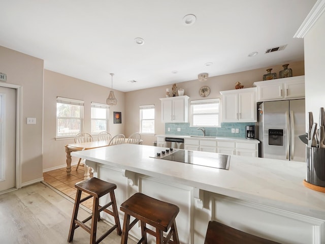 kitchen with decorative light fixtures, sink, a breakfast bar area, white cabinets, and stainless steel appliances