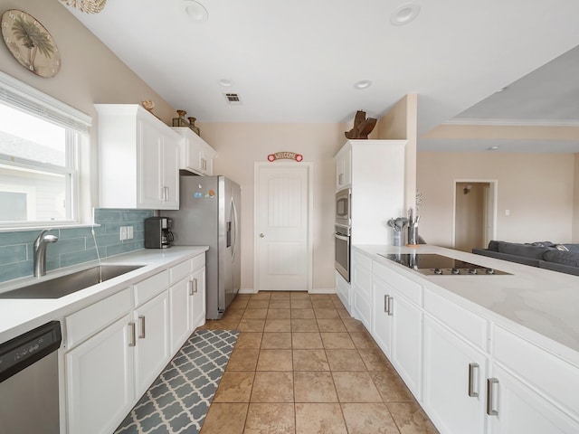 kitchen with sink, light tile patterned floors, stainless steel appliances, tasteful backsplash, and white cabinets