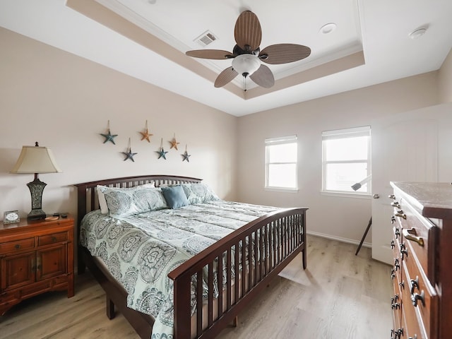 bedroom with a tray ceiling, ornamental molding, ceiling fan, and light wood-type flooring