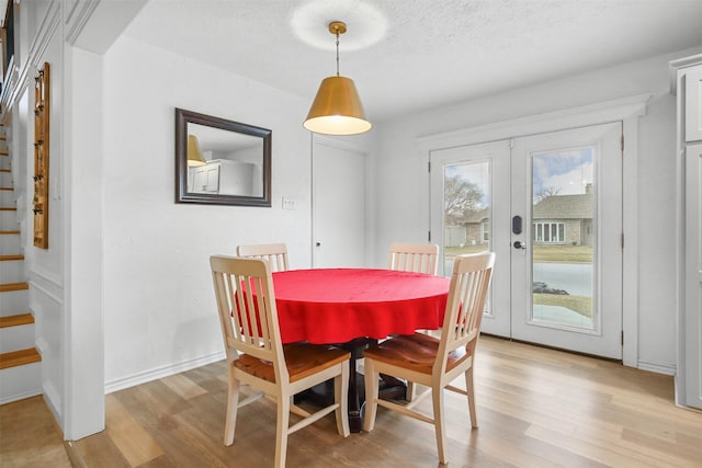 dining room featuring a textured ceiling, light wood-type flooring, and french doors